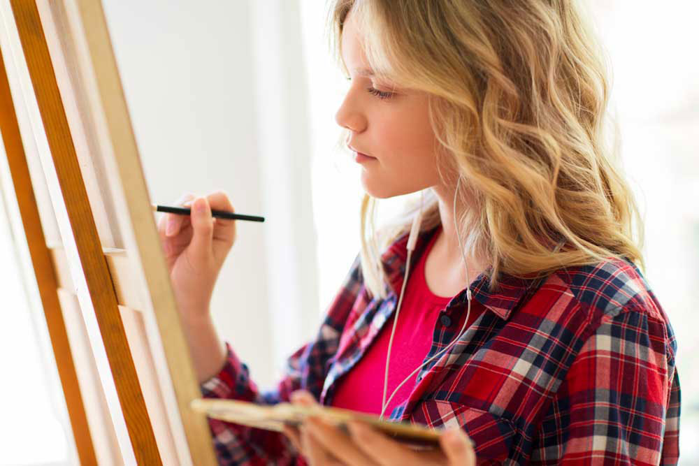 Une étudiante qui peint sur une toile et un chevalet
